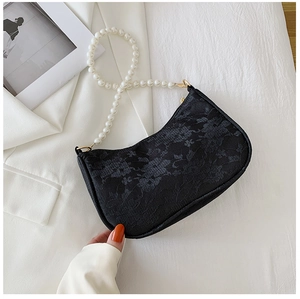 Close-up of black lace underarm bag with large white pearl strap on white suit background