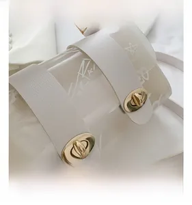 Detail showing two golden oval metal twist locks on a beige graffiti pattern crossbody bag