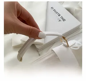 Detail of white leather handle with gold metal rings on a transparent jelly tote bag