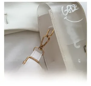 Detail of golden metal hooks and transparent PVC panel with smiley and GOOD print