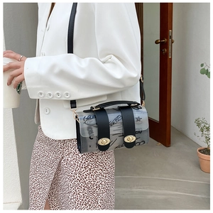 Detail of transparent PVC crossbody bag with black graffiti patterns and gold twist locks