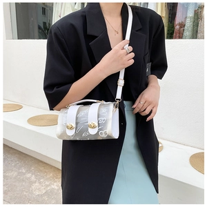 Close-up of white graffiti print on transparent PVC handbag with gold turn-lock closure