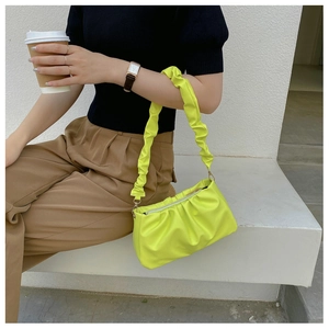 Close-up of vibrant neon yellow pleated cloud bag with scrunchie strap and zipper detail
