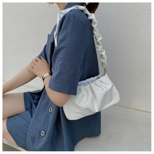 Close-up of a white pleated cloud bag featuring textured leather and a stylish wide strap