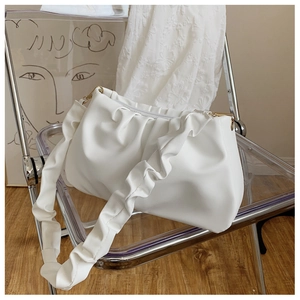 Close-up of white ruched cloud bag with pleated strap and gold metal D-ring buckle