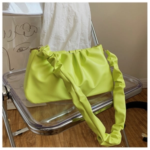 Detail of neon green pleated cloud bag with soft PU leather texture on modern chair