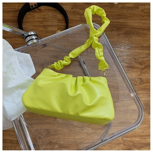 Close-up of fluorescent green ruched cloud bag with matching scrunchie strap and gold metal hooks
