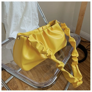 Close-up of bright yellow pleated cloud bag with shiny PU leather and ruffled shoulder strap