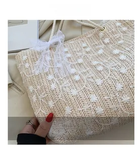 Detailansicht der Strohtasche mit Gänseblümchen-Stickerei und eleganter Spitzenschleife