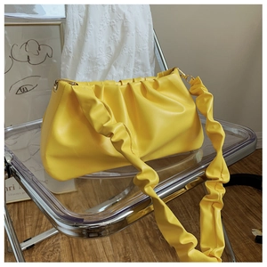 Detail of yellow pleated cloud bag showing soft PU leather texture and gold metal rings