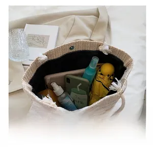 Makro-Detail der beigen Strohtasche mit weißer Spitze und großem Fassungsvermögen