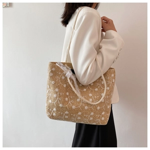Stroh-Schultertasche mit weißer Blumenstickerei und Spitzenband-Verzierung im Detail