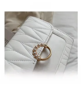 Détail du sac en cuir matelassé crème avec anneau doré orné de perles élégantes