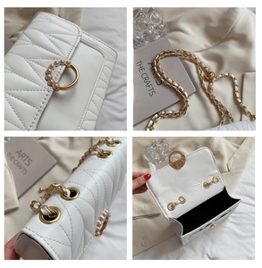 Detail of white chevron quilted crossbody bag with pearl buckle and gold chain strap