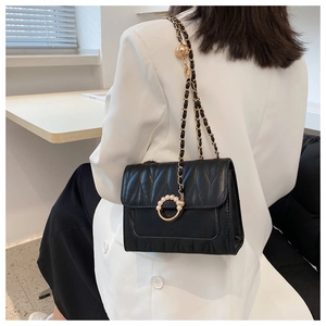 Détail du sac bandoulière matelassé noir avec boucle perle et chaîne dorée