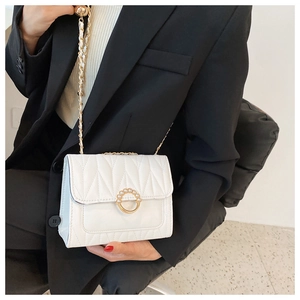 Detailed close-up of white quilted crossbody bag with pearl-inlaid metal ring clasp