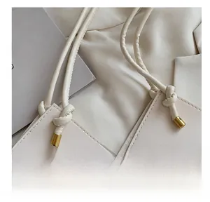 Macro detail of meticulous stitching and knotted handle on a beige leather handbag