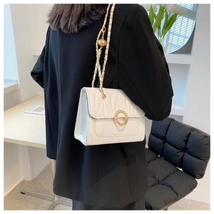 Detail of white quilted crossbody bag with pearl ring buckle and adjustable chain strap