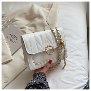 Close-up of white quilted crossbody bag with gold chain strap and pearl ring buckle
