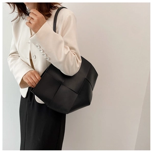 Detail of minimalist black woven tote bag with wide strap and spacious open design