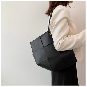 Detail of black woven leather tote bag with wide strips and metallic buckle hardware