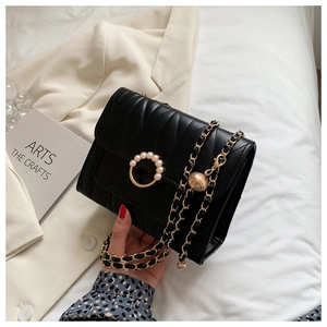 Detail of black quilted leather crossbody bag with pearl gold buckle and chain strap