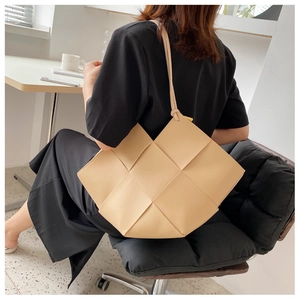 Detail view of beige woven leather tote bag texture and long shoulder straps