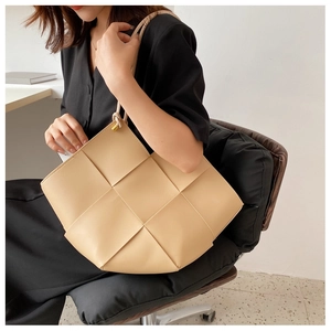 Detailed view of beige woven leather tote bag shown on model for size perspective