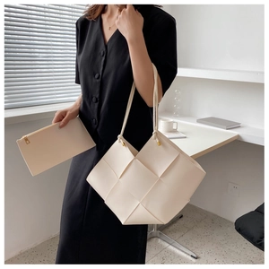 Detail of cream woven tote bag showing wide grid texture and matching inner zipper pouch
