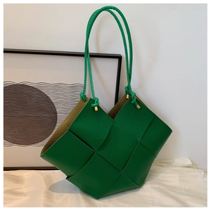 Detail of green woven tote bag featuring thick leather weave and golden metal knots