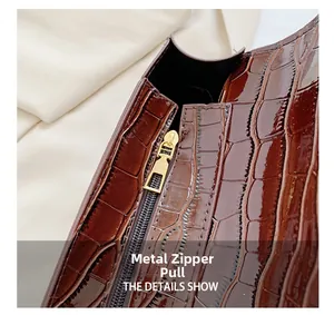 Detail showing the golden hardware zipper pull on dark brown crocodile texture handbag