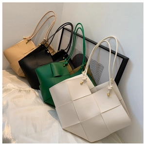 Detail of woven tote bags in four colors with knotted straps and gold metal tips