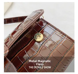 Detail of golden magnetic clasp on a brown crocodile pattern leather baguette bag