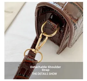 Detail showing the detachable shoulder strap with golden metal clasp on brown croc bag