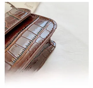 Close-up of brown crocodile pattern shoulder bag showing precise stitching and leather texture