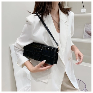 Detail of black crocodile pattern crossbody bag with flap and decorative buckle