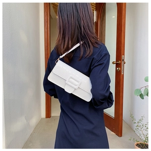Detailed side view of a white crocodile embossed baguette bag with a stylish square buckle