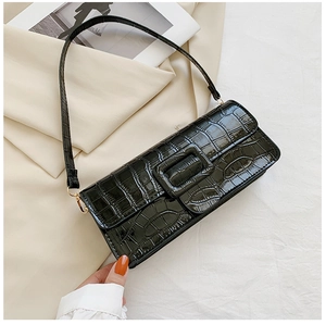 Detail of glossy black crocodile pattern shoulder bag on silk fabric background