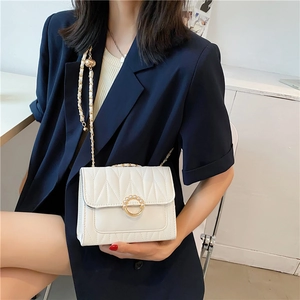 Chic white quilted crossbody bag with pearl gold lock and chain strap on female model