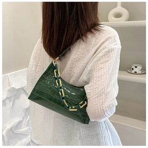 Close-up of dark green crocodile texture baguette bag with chunky gold chain