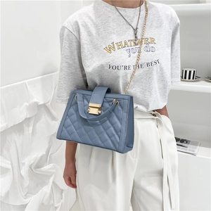 Sac baguette bleu en cuir matelassé avec chaîne dorée porté comme sac à bandoulière