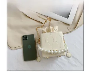 Detail of cream bucket bag with wavy texture, pearl handle and a smartphone for size reference