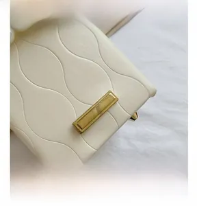 Detailed macro view of the cream white bucket bag with wave embossing and pearl handle