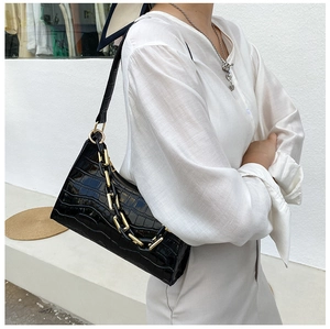 Detail of black crocodile texture shoulder bag with stylish gold chain and zipper closure