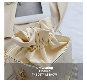 Close-up of cream drawstring bucket bag with elegant pearl details and soft leather texture
