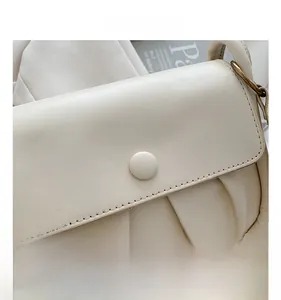 Close-up of beige ruched cloud bag with vintage gold chain and magnetic snap buckle