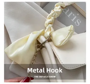 Detail of creamy cloud bag showing satin bow handle and golden metal hook hardware