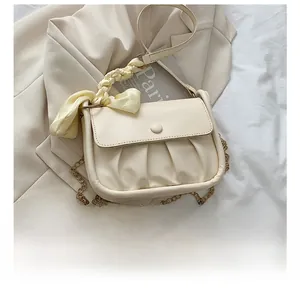 Detail of cream pleated cloud bag with silk scarf handle and gold chain strap comparison