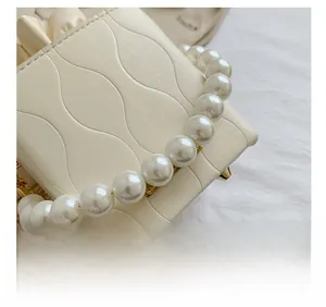 Macro detail of cream bucket bag with wavy embossed leather and pearl handle