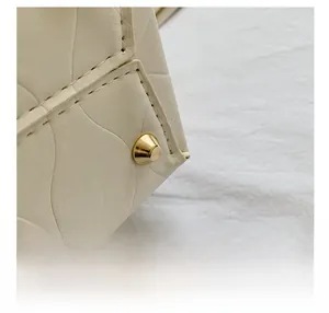 Detail of cream bucket bag with quilted texture and gold anti-wear bottom rivet